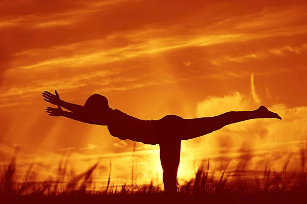 Mujer haciendo yoga contra la puesta del sol cielo —  Fotos de Stock