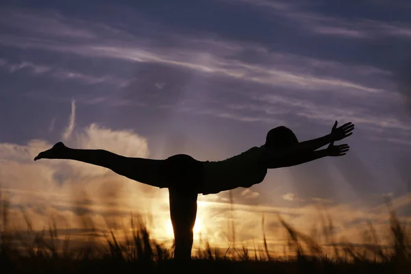 Mujer haciendo yoga contra la puesta del sol cielo —  Fotos de Stock