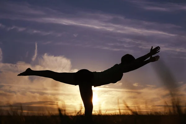 Mujer haciendo yoga contra la puesta del sol cielo —  Fotos de Stock