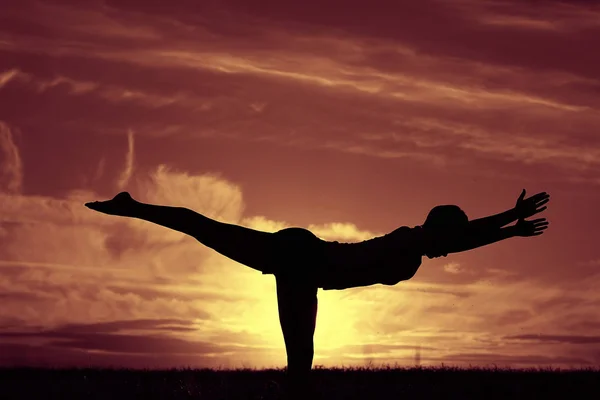 Günbatımı gökyüzü karşı yoga yaparken kadın — Stok fotoğraf