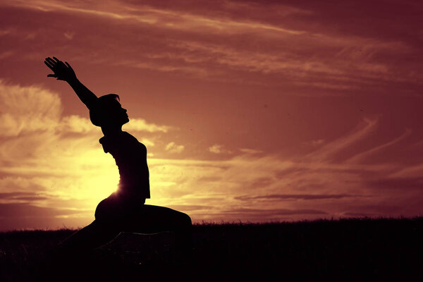 Silhouette of young woman doing yoga against colorful sunset sky, concept of harmony