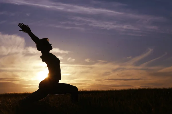 Mulher fazendo ioga contra o céu por do sol — Fotografia de Stock