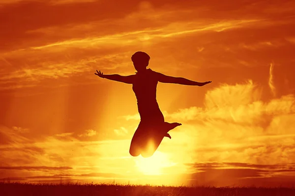 反对的夕阳的天空跳跃的女人 — 图库照片