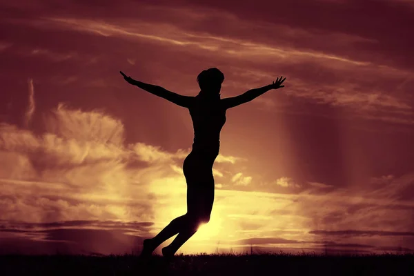 Mujer saltando contra el cielo puesta del sol — Foto de Stock