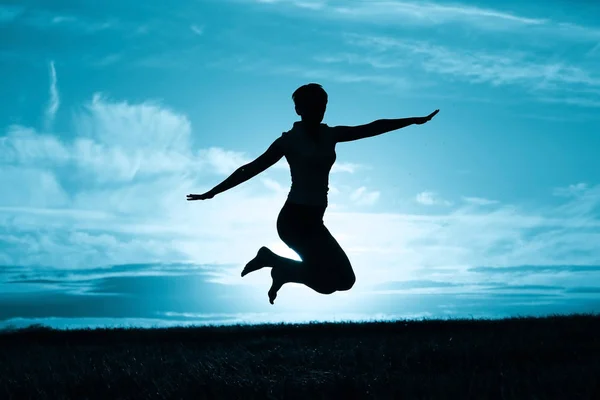 Mulher saltando contra o céu por do sol — Fotografia de Stock
