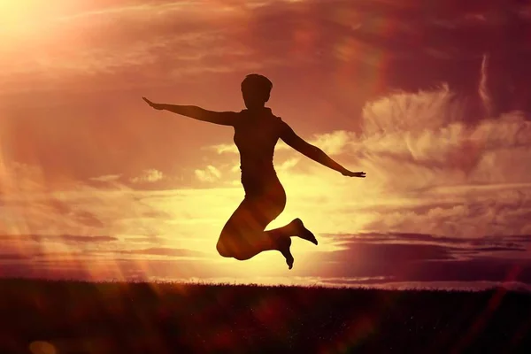 Mujer saltando contra el cielo puesta del sol — Foto de Stock