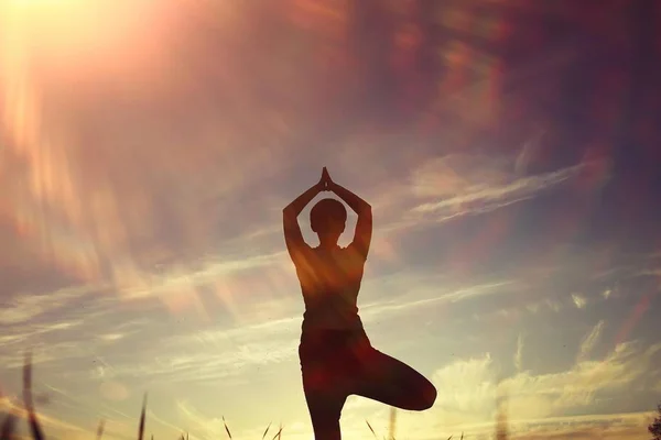 Mujer haciendo yoga contra la puesta del sol cielo —  Fotos de Stock