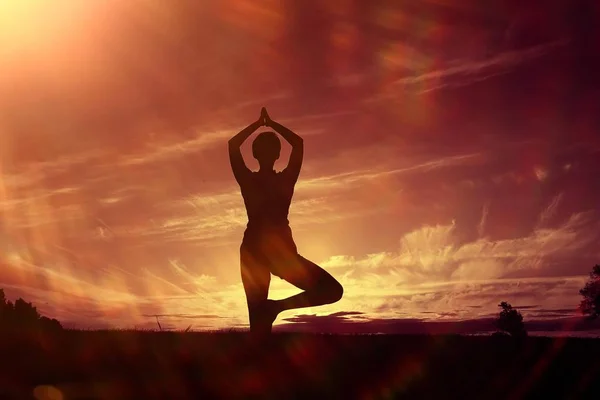 女人做瑜伽反对的夕阳的天空 — 图库照片