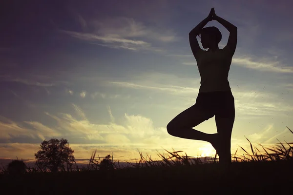 Mujer haciendo yoga contra la puesta del sol cielo —  Fotos de Stock