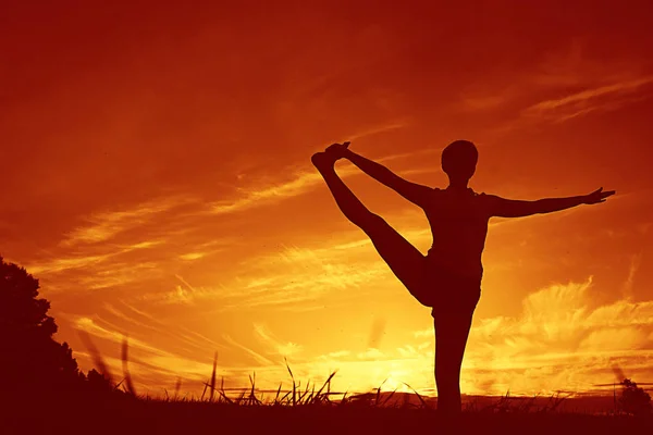 Mujer haciendo yoga contra la puesta del sol cielo —  Fotos de Stock