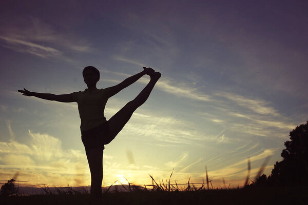 woman doing yoga against sunset sky