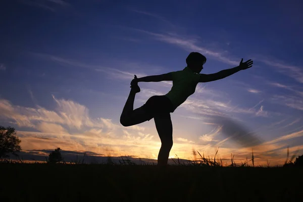 Mujer haciendo yoga contra la puesta del sol cielo —  Fotos de Stock