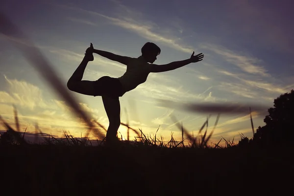 女人做瑜伽反对的夕阳的天空 — 图库照片