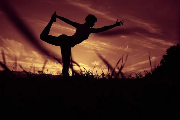 Mujer haciendo yoga contra la puesta del sol cielo —  Fotos de Stock