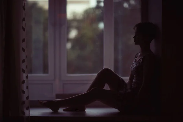 Woman sitting on windowsill — Stock Photo, Image