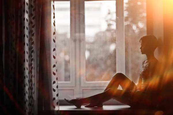 Woman sitting on windowsill — Stock Photo, Image