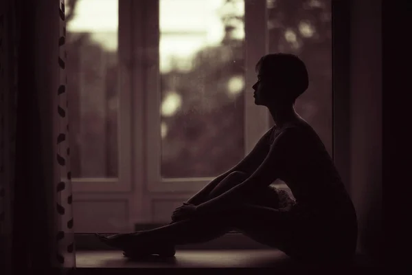 Woman sitting on windowsill — Stock Photo, Image
