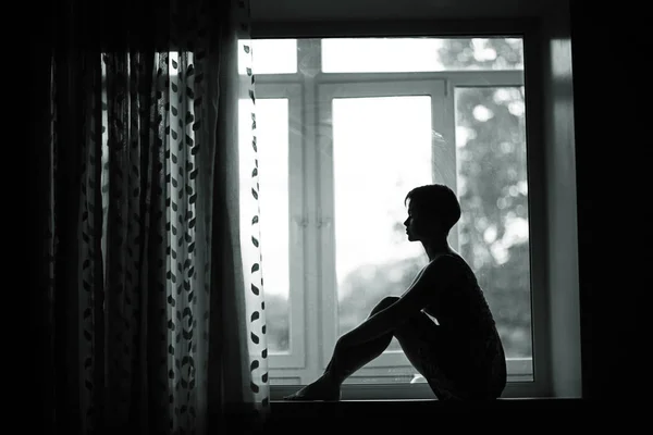 Woman sitting on windowsill — Stock Photo, Image