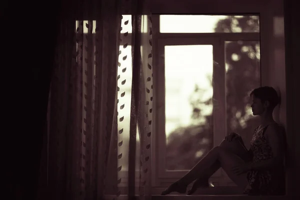 Woman sitting on windowsill — Stock Photo, Image
