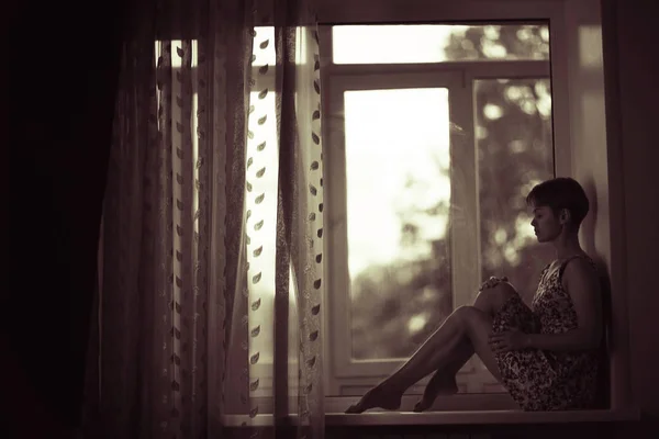 Woman sitting on windowsill — Stock Photo, Image