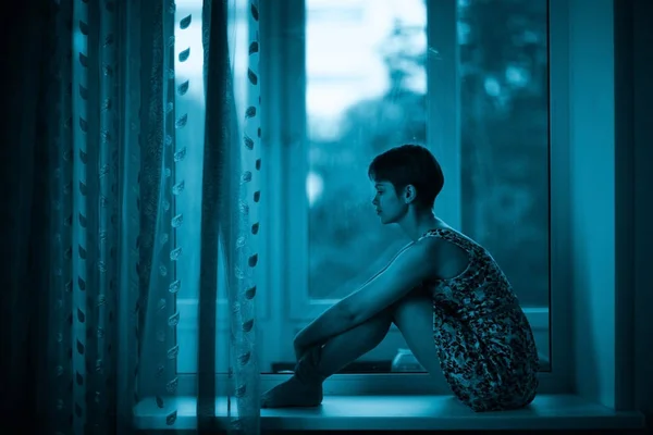 Woman sitting on windowsill — Stock Photo, Image