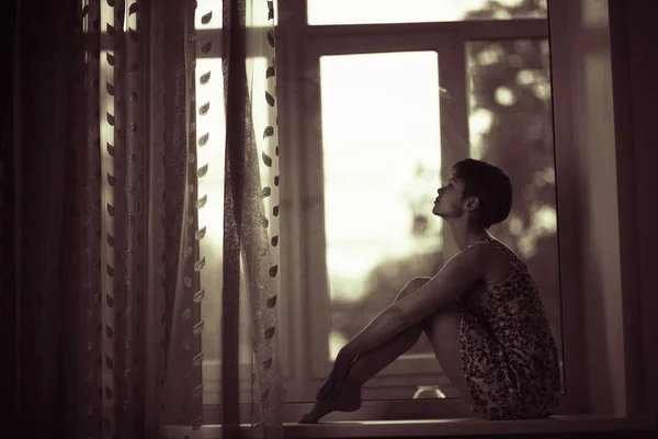 Woman sitting on windowsill — Stock Photo, Image