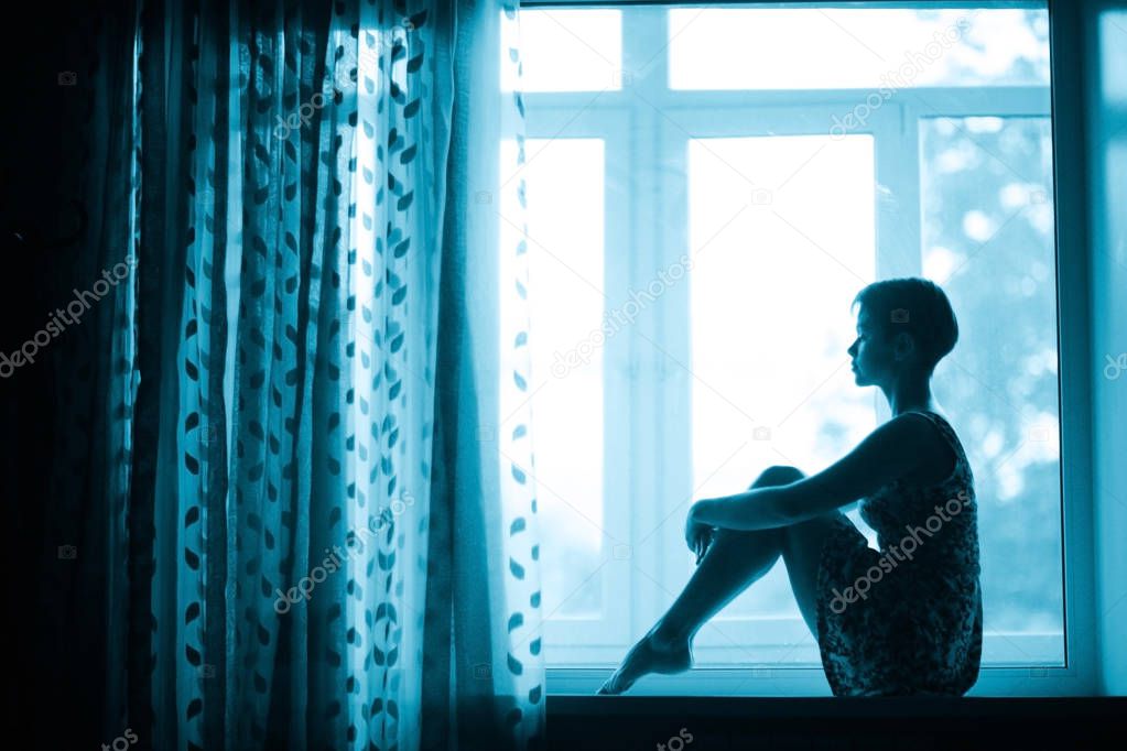 woman sitting on windowsill 