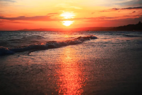 Vågor på stranden vid solnedgången — Stockfoto