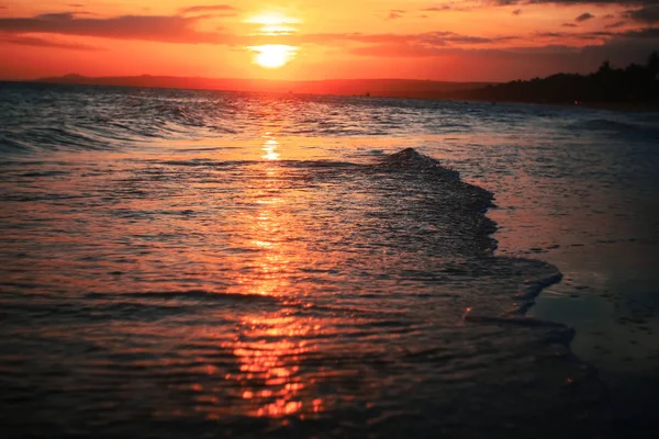 Vågor på stranden vid solnedgången — Stockfoto