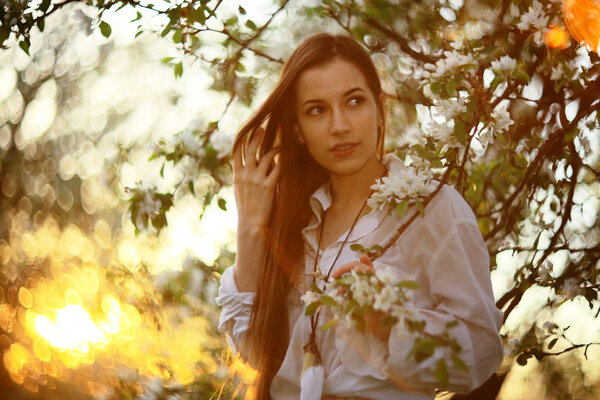Portrait of young beautiful woman in spring garden with apple blossom