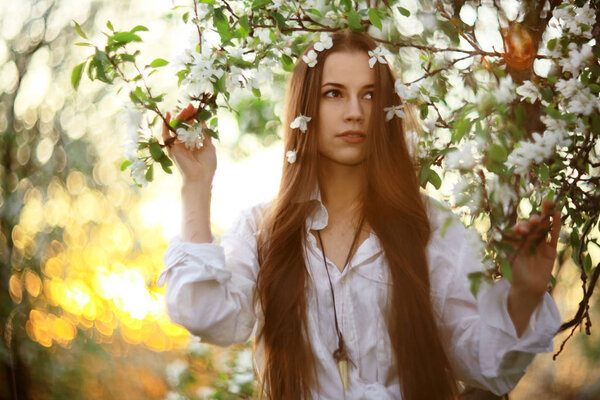 Portrait of young beautiful woman in spring garden with apple blossom