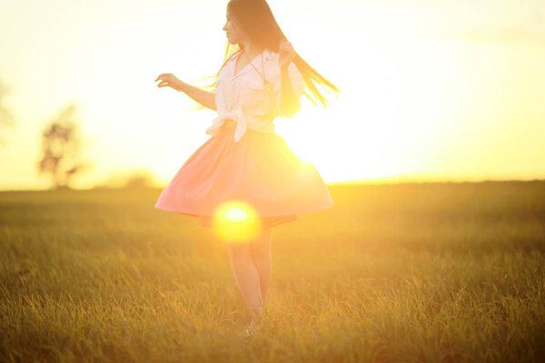 Portrait of young woman in rural field at sunset. Summer vacation and happiness concept