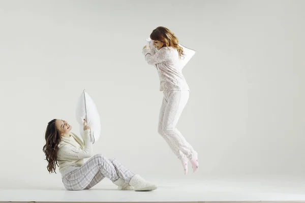 Jonge vrouwen in pyjama's vechten met kussens — Stockfoto