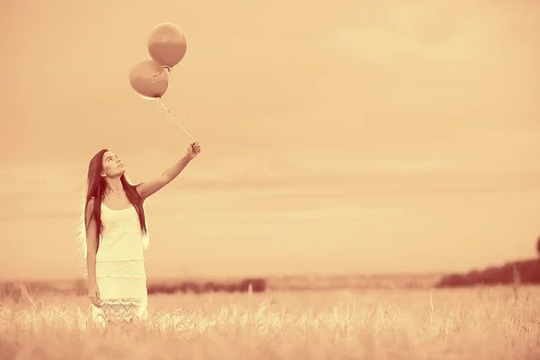 Жінка в пшеничному полі з літаючими кульками — стокове фото