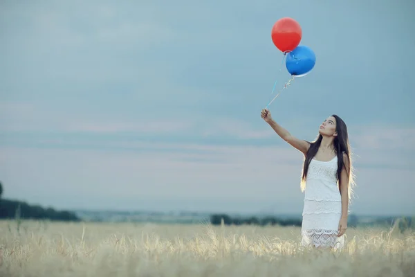 Femme dans un champ de blé avec des ballons volants — Photo