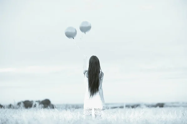 Woman in wheaten field with flying balloons — Stock Photo, Image