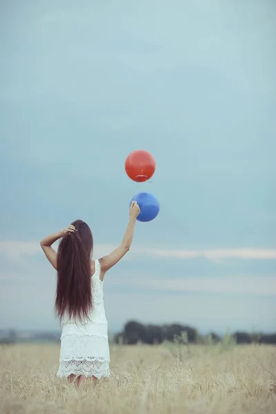 Kvinna i wheaten fältet med flygande ballonger — Stockfoto