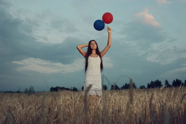 Mujer en campo de trigo con globos voladores —  Fotos de Stock