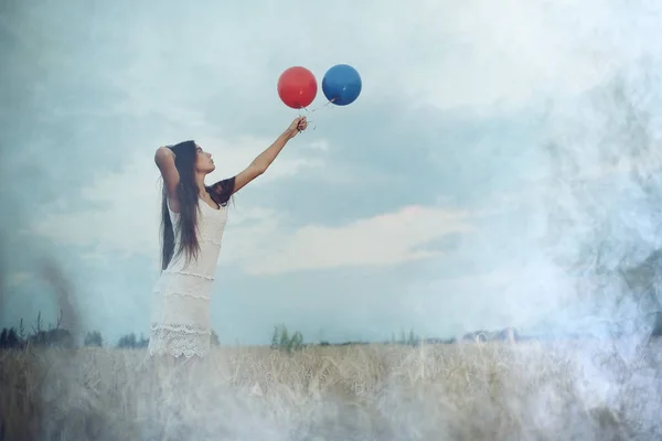 Vrouw in wheaten veld met vliegende ballons — Stockfoto