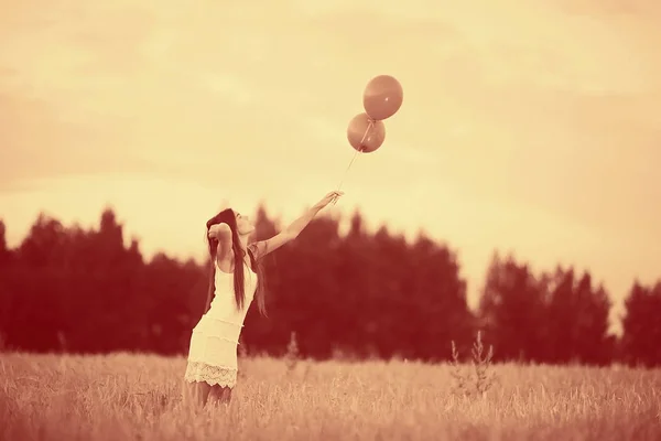 Mujer en campo de trigo con globos voladores — Foto de Stock