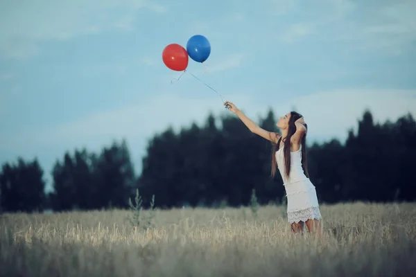 Femme dans un champ de blé avec des ballons volants — Photo