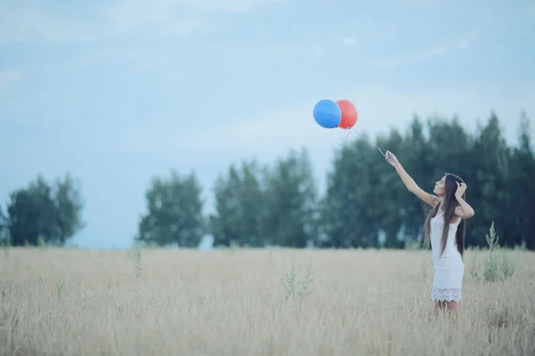 Mujer en campo de trigo con globos voladores — Foto de Stock