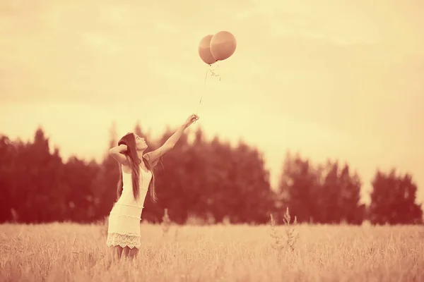 Женщина на пшеничном поле с летающими воздушными шарами — стоковое фото