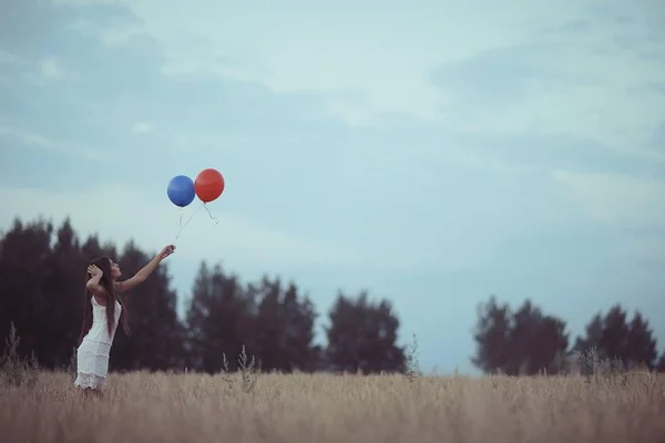 Vrouw in wheaten veld met vliegende ballons — Stockfoto