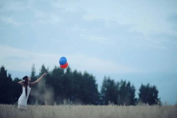 Vrouw in wheaten veld met vliegende ballons — Stockfoto
