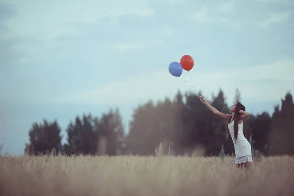 Woman in wheaten field with flying balloons — Stock Photo, Image