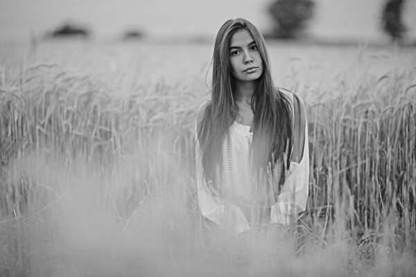 Beautiful young woman with long hair posing in wheaten field