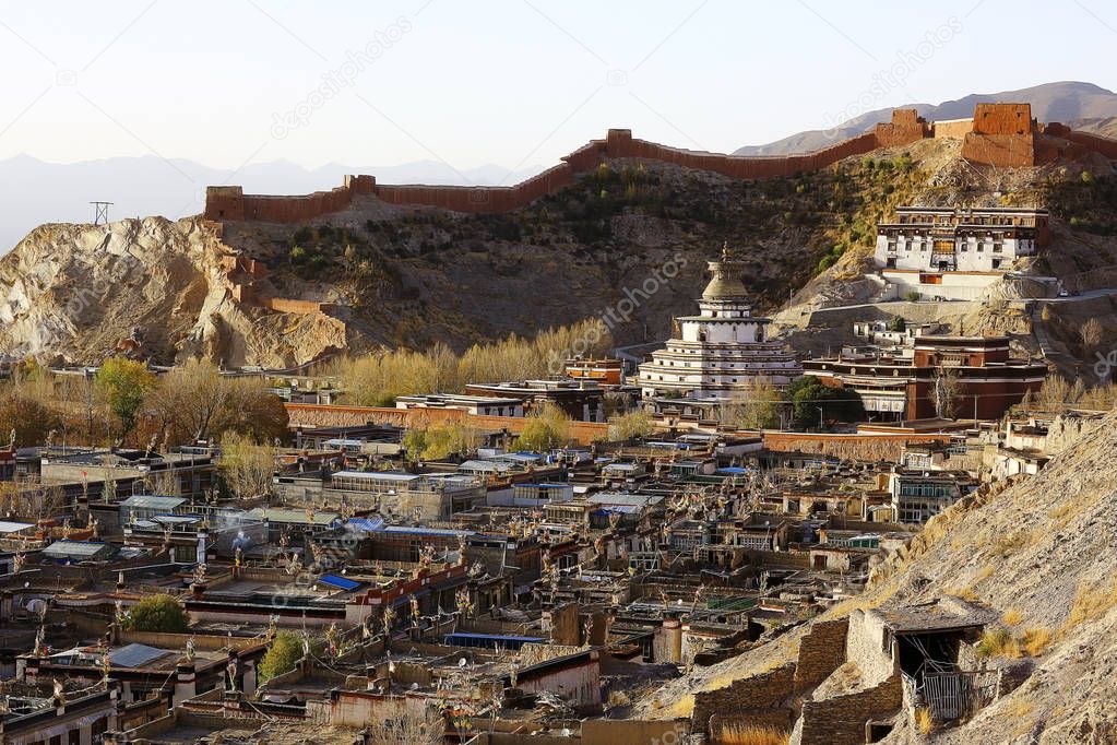 picturesque landscape with Tibetan plateau mountains and small old buildings on foreground 