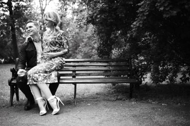 güzel genç kadın ve yakışıklı adam parkta bankta oturuyor. Çift tarihte tr açık, siyah ve beyaz 