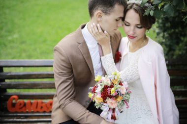 güzel genç gelin buketi çiçek ve yakışıklı Damat Düğün gününde parkta bankta oturmuş ile